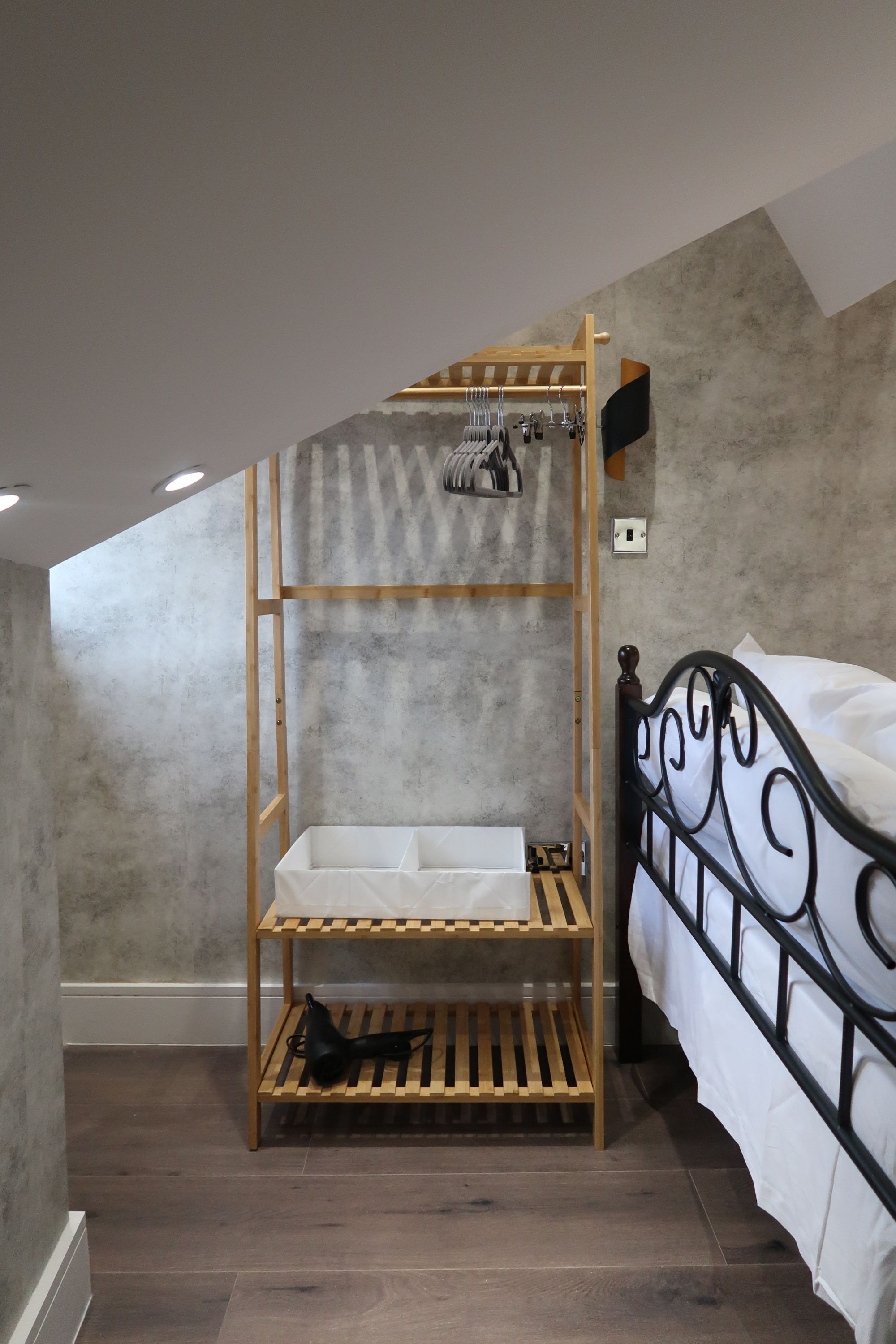 A bunk bed with a wooden ladder, a white mattress, and a black metal headboard.