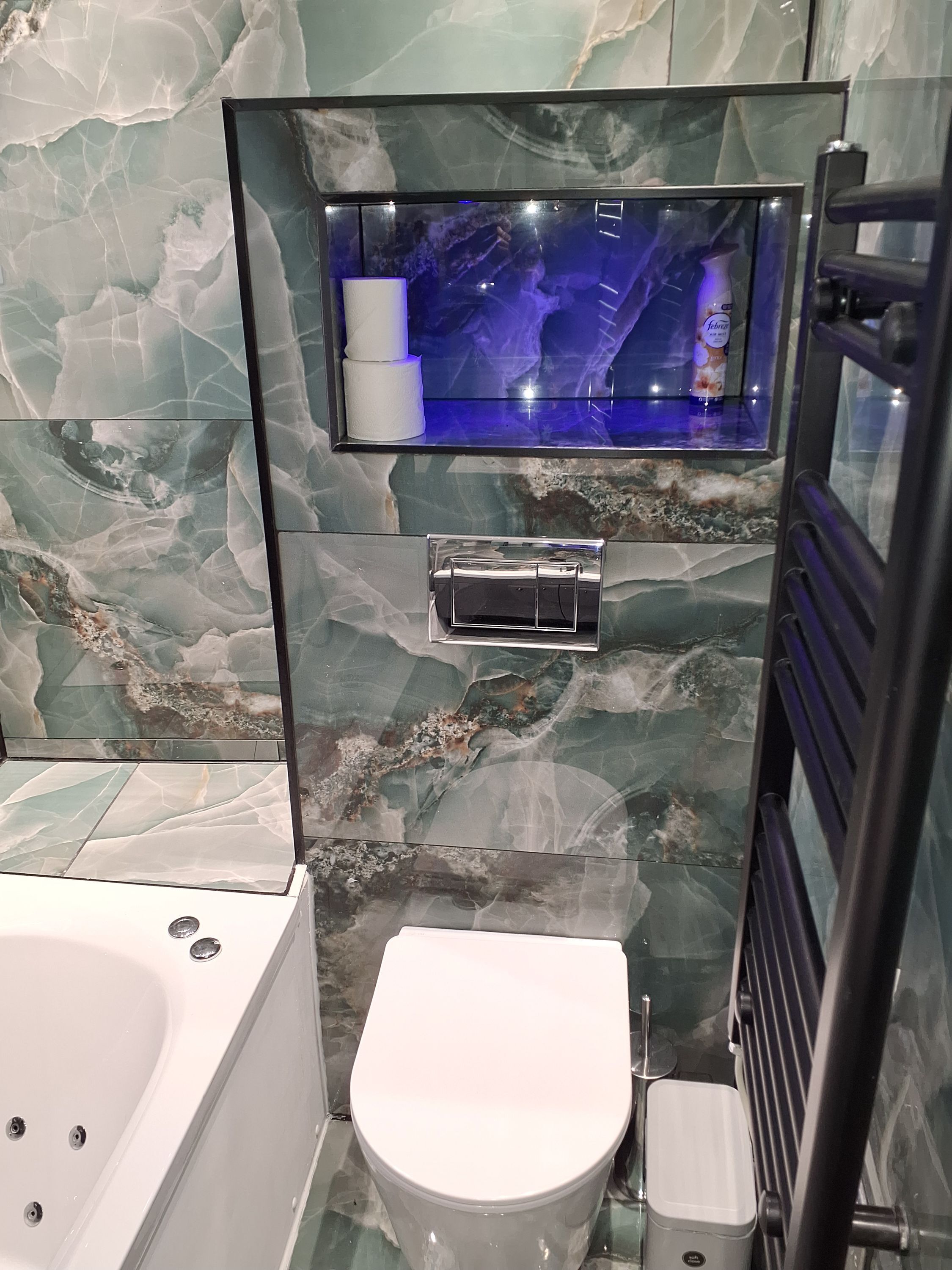 A modern bathroom with a marble backsplash, a glass-enclosed shower, and a white toilet.