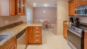 A kitchen with wooden cabinets, granite countertops, a dishwasher, a stove, and a microwave. - Breathless Backyard Amazing Pool (Largo)