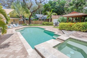 A rectangular swimming pool with a tiled deck, surrounded by palm trees and a gazebo. - Breathless Backyard Amazing Pool (Largo)