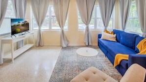 A living room with a blue sofa, a white coffee table, a TV on a stand, and a patterned rug. - Breathless Backyard Amazing Pool (Largo)
