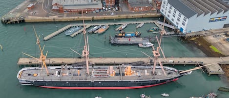 Un grand navire était amarré dans un port, et plusieurs petites embarcations se trouvaient à proximité.