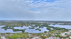 An aerial view of a coastal area with numerous small islands surrounded by water, a dense urban area in the background, and a clear sky with scattered clouds.