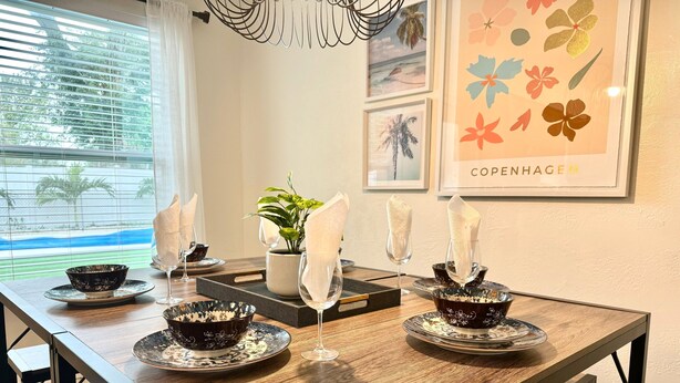 A dining table set with black and white patterned bowls, wine glasses, and napkins.