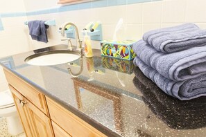 A bathroom with a sink, a towel rack, a soap dispenser, and a tissue box.