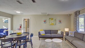 Una sala de estar moderna con un sofá gris, sillas azules, una mesa de comedor redonda y una pequeña mesa de centro blanca.
