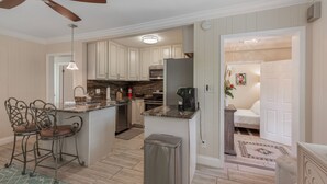 A kitchen with a central island, bar stools, a ceiling fan, and a microwave. - Private Villa With Courtyard (Clearwater)