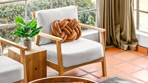 Une pièce chaleureuse avec une chaise en bois, une petite table sur laquelle est posé un plateau, et une plante en pot.
