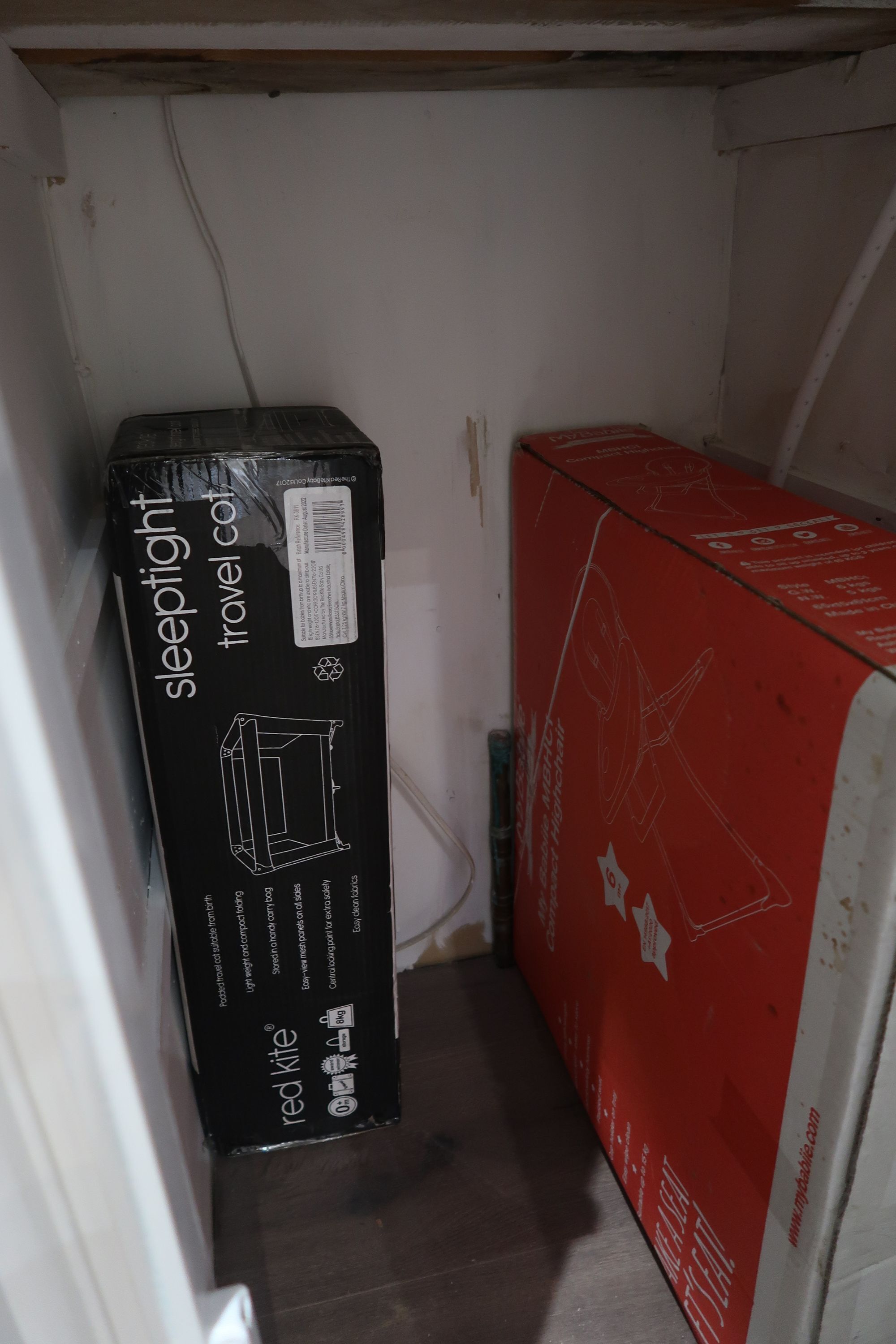 Un pasillo estrecho con una maleta negra y una caja roja, presumiblemente con objetos de viaje.