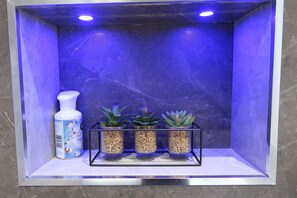 A bathroom with a blue-lit vanity, a white bottle, and three potted succulents. - Quaint Retreat in Sherborne s Historic District (Sherborne)
