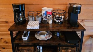Una estación de café con cafetera, tazas y un letrero que dice 'El café me mantiene activo hasta que es hora de vino'.