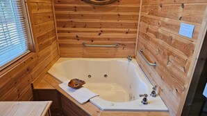 Un baño de cabaña de madera con una bañera, un tocador de madera, una toalla y un espejo.