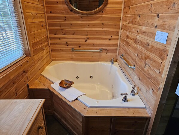Ein Badezimmer einer Holzhütte mit Badewanne, Holzwaschtisch, Handtuch und Spiegel.