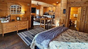Interior d'una cabana de fusta amb una zona d'estar acollidora, una cuina i un bany.