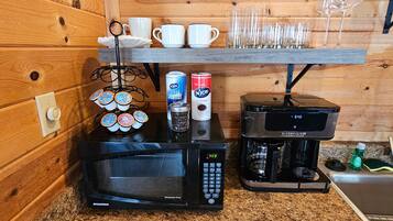 A kitchen with a microwave oven, coffee maker, and various coffee pods.