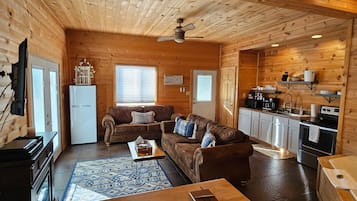 Ein gemütliches Blockhaus-Interieur mit Wohnbereich, Küchenzeile und Esstisch.