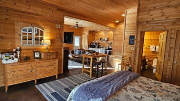 Ein Holzblockhaus mit gemütlichem Wohnbereich, einer Küche und einem Badezimmer.