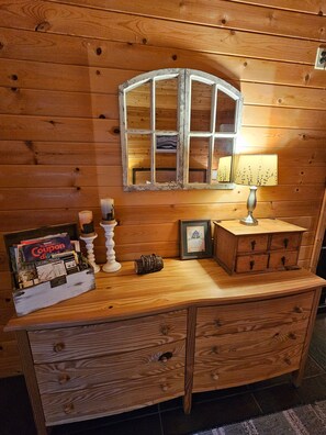 A wooden dresser with a mirror, a lamp, and a framed picture.