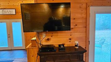A wooden interior with a flat-screen TV mounted on a wall, a fireplace with a glass door, and a sign that reads "this is our happy place."