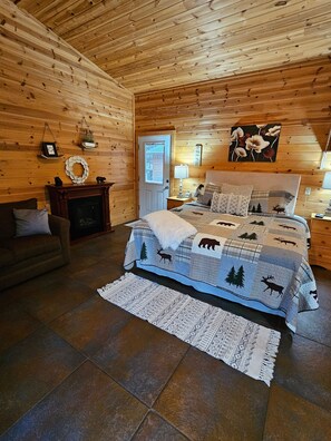 Un dormitorio rústico de cabaña con una cama, una chimenea y una ventana.