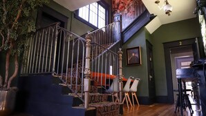 Una escalera con barandillas de metal decorativas, una planta en maceta y vista a una puerta con el número 2.