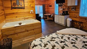 A cabin interior with a wooden interior, a bathtub, a dining area, and a kitchen. - Honey Bear Haven Suite 1 (Eureka Springs)