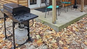A wooden cabin with a covered porch, a grill, and outdoor seating. - Honey Bear Haven Suite 1 (Eureka Springs)