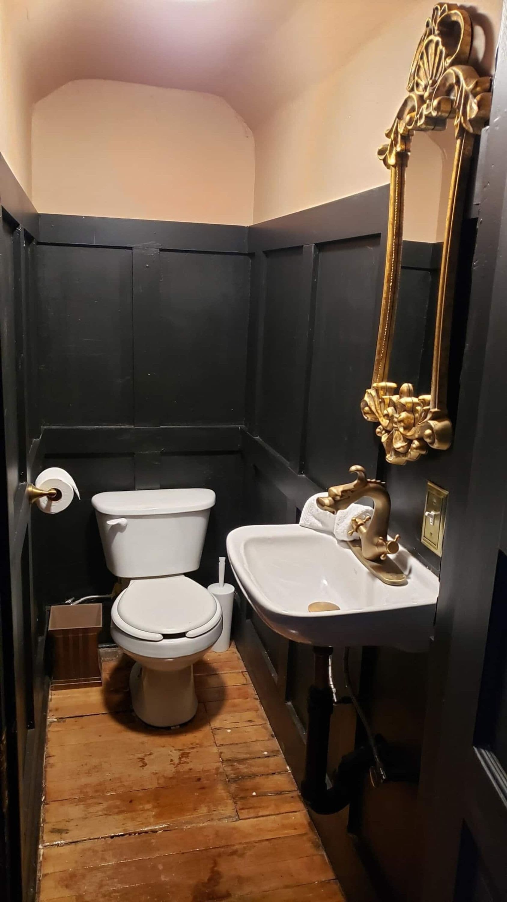 Ein kleines Badezimmer mit Toilette, Waschbecken und einem dekorativen Spiegel.