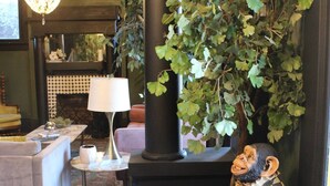 A living room with a fireplace, a chandelier, a sofa, a lamp, and a monkey statue. - Casa Mina 5 Central Rio Grande Historic Dist (El Paso)