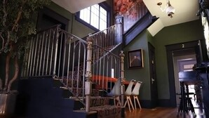 A staircase with ornate metal railings, a potted plant, and a dining area with chairs and a table. - Casa Mina 5 Central Rio Grande Historic Dist (El Paso)