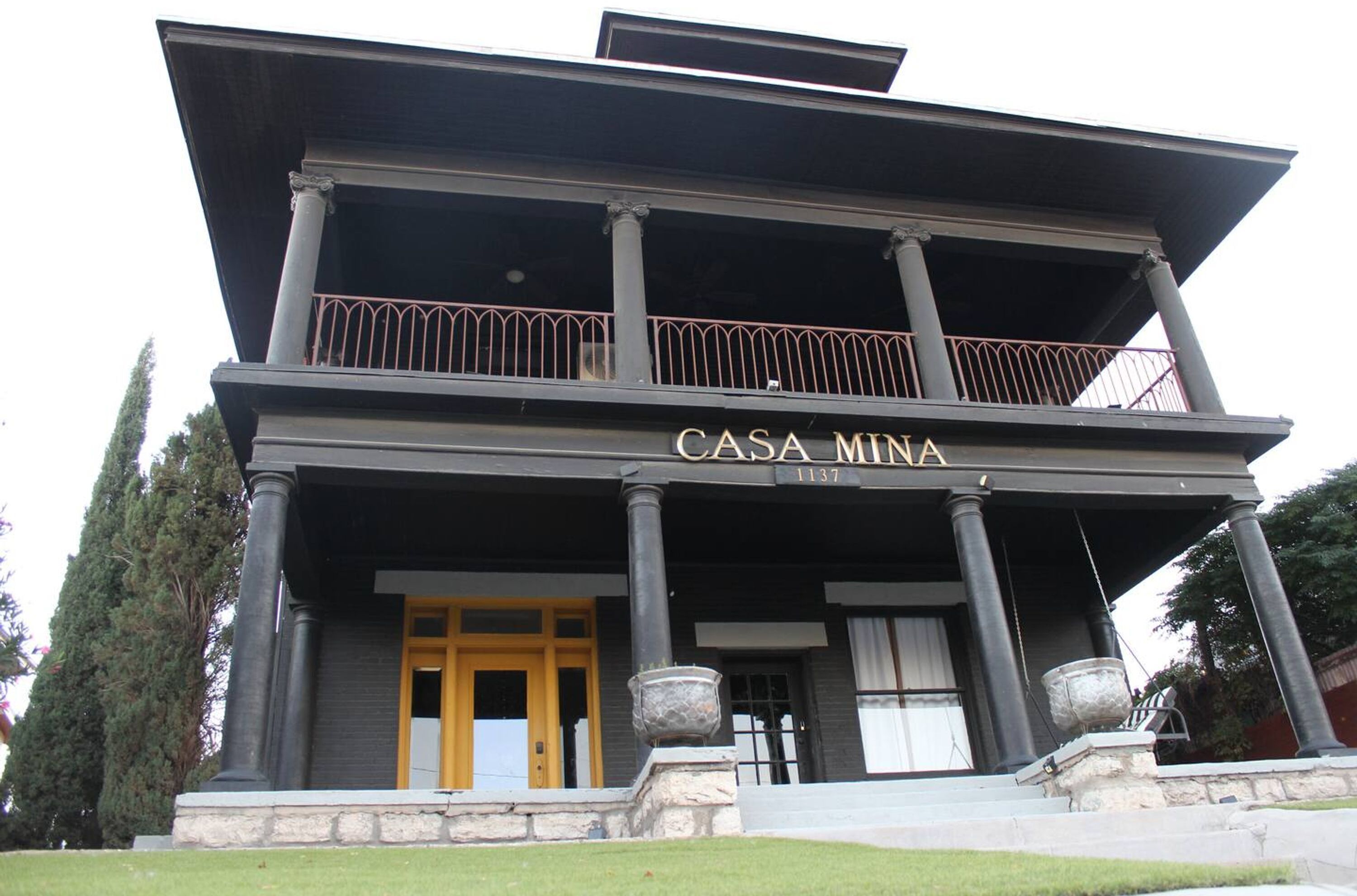En toetagers bygning med balkon, søjler og et skilt, der siger "CASA MINA".