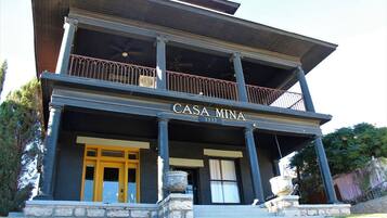 Een gebouw met twee verdiepingen, een balkon, zuilen en een bord met de tekst 'CASA MINA'.