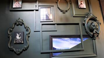 A wall with various framed pictures and decorative mirrors.