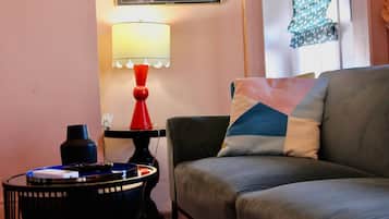 A living room with a grey sofa, a red lamp, a small black table with a vinyl record player, and a framed picture on the wall.