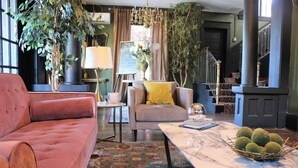 A cozy living room with a plush red sofa, a grey armchair with a yellow pillow, and a marble coffee table with a decorative bowl. - Casa Mina 4 Central Rio Grande Historic District (El Paso)