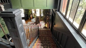A staircase with patterned carpet leading to a room with green walls and a window overlooking a brick building. - Casa Mina 4 Central Rio Grande Historic District (El Paso)