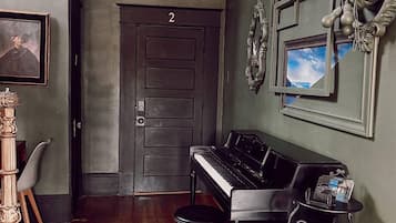 A room with a piano, a door labeled '2', and a chandelier.
