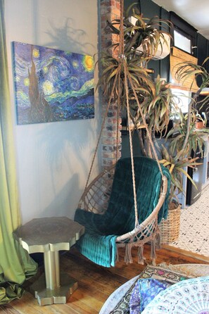 A room with a hanging chair, a painting on the wall, and a potted plant. - Casa Mina 3 Central Rio Grande Historic Dist (El Paso)