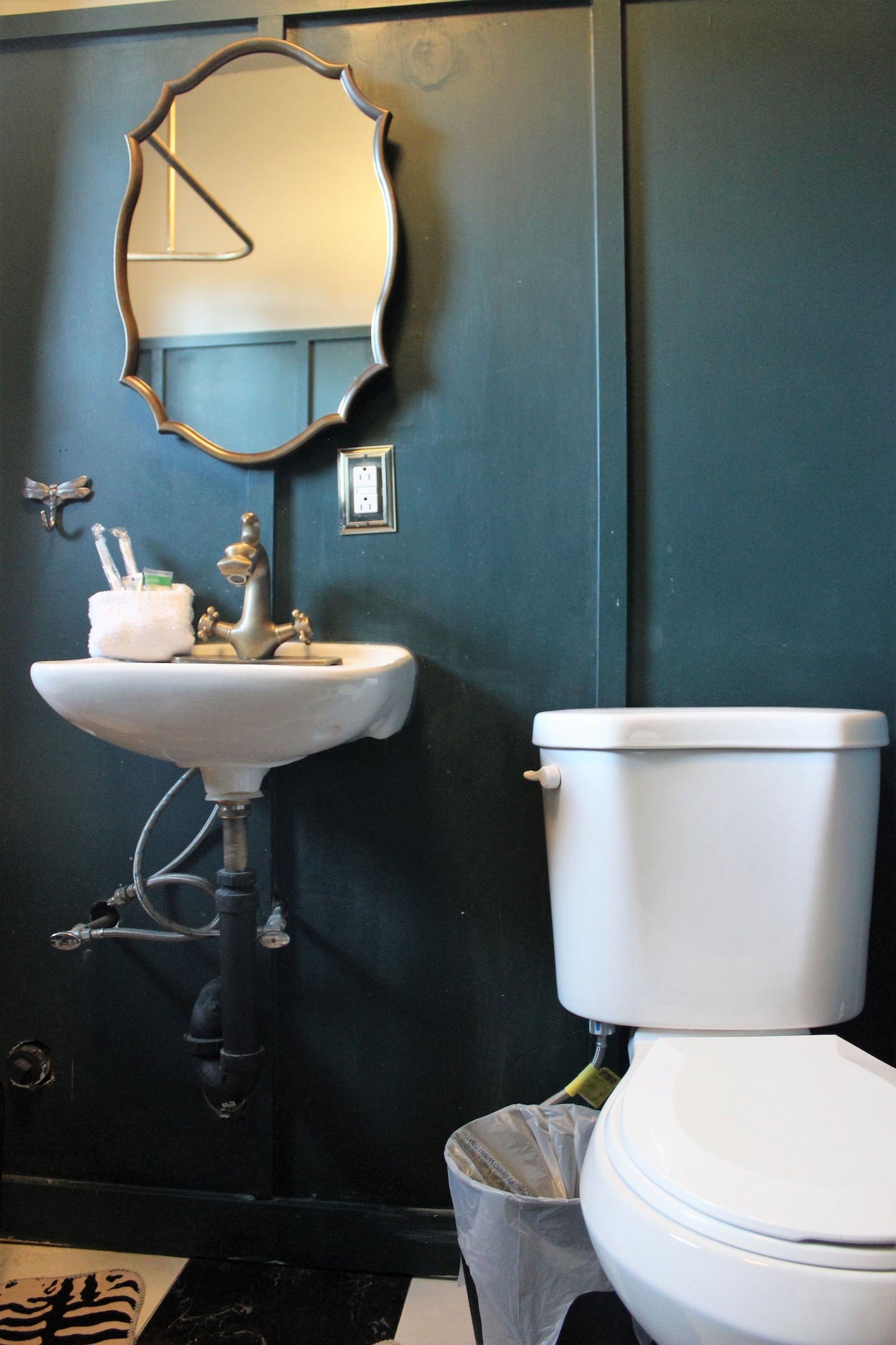 Une salle de bain avec un lavabo blanc, des toilettes et un miroir au mur.