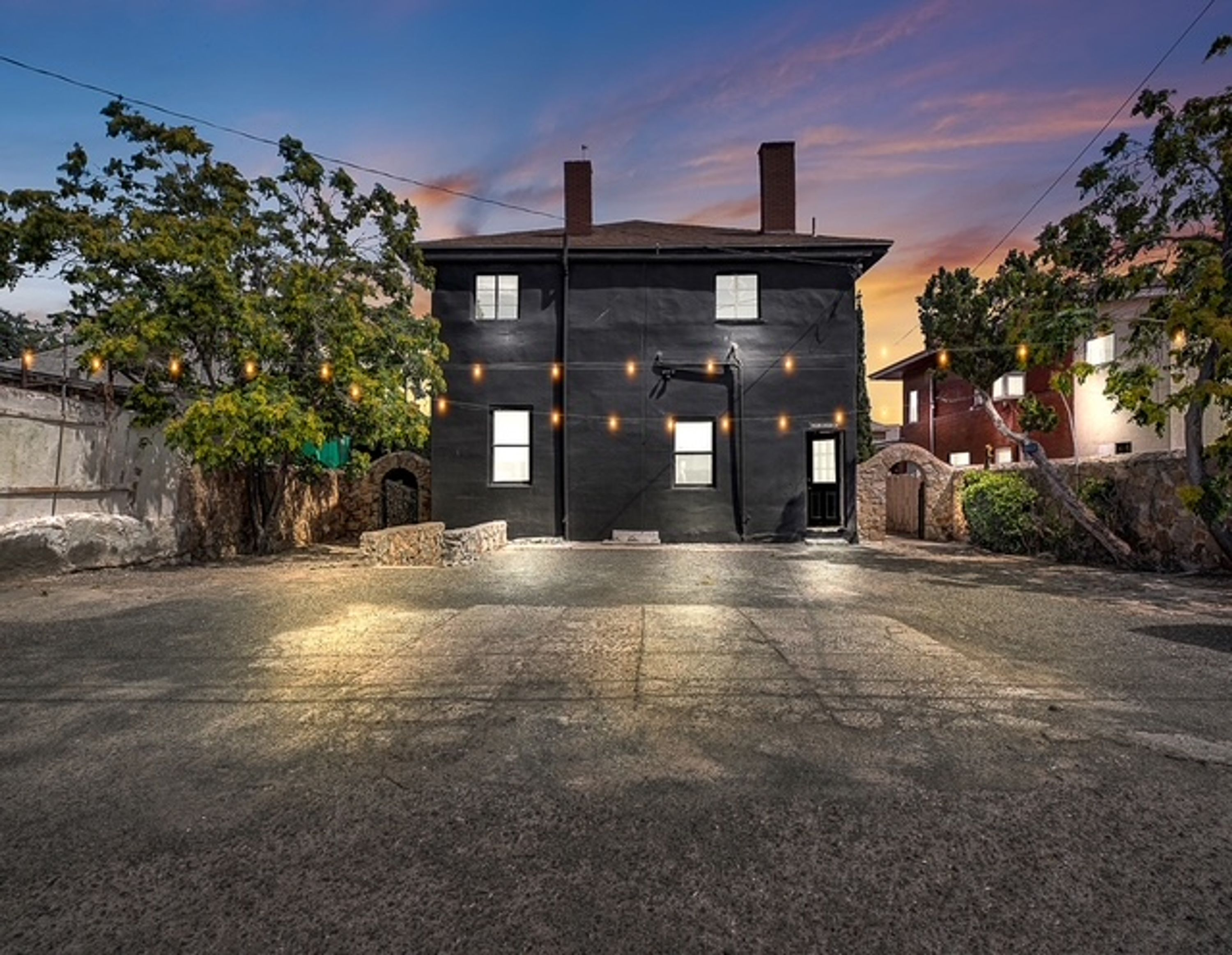 A two-story building with a flat roof, multiple windows, and a paved driveway.