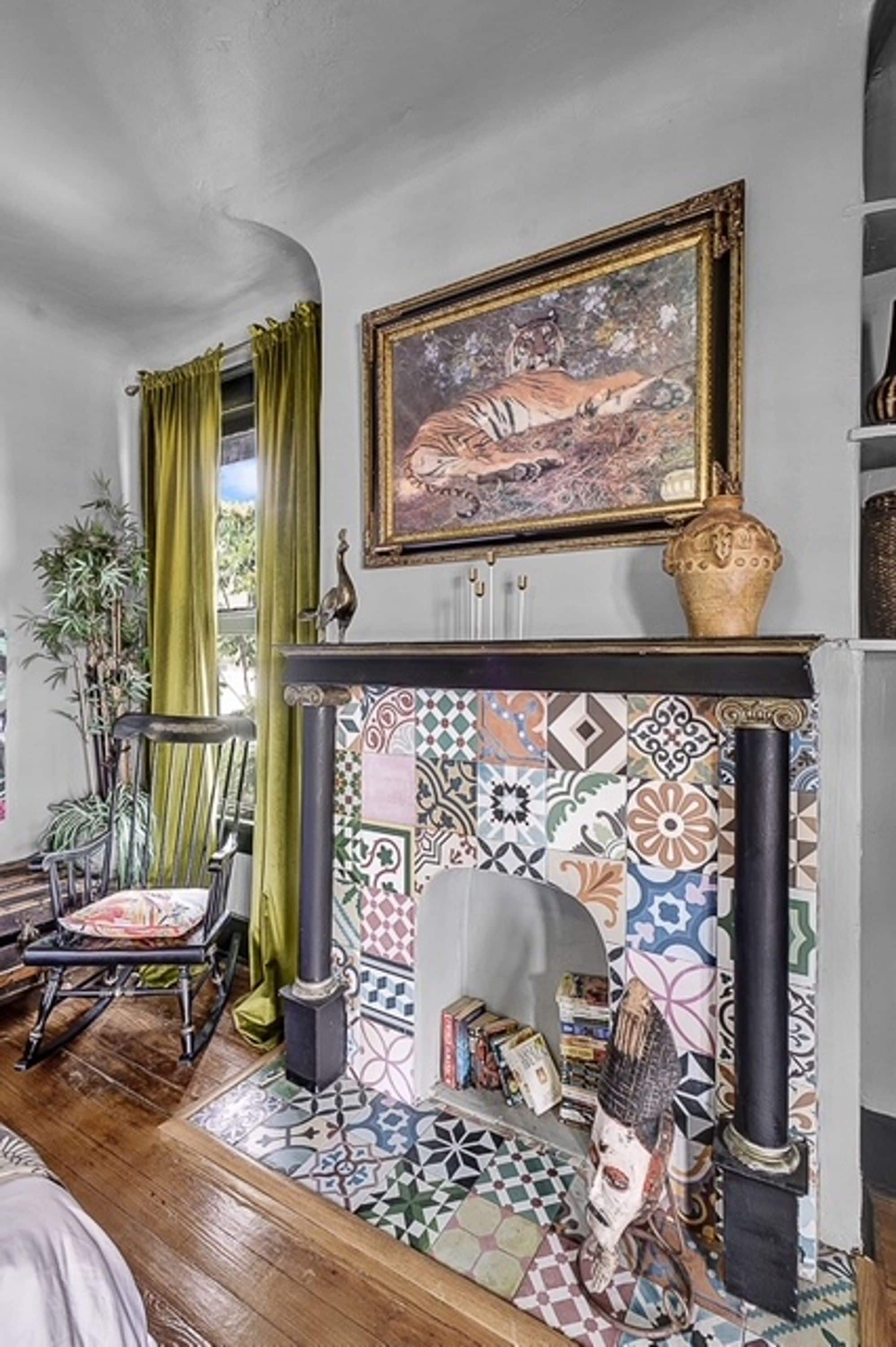 A room with a fireplace, a painting above it, and a patterned floor.