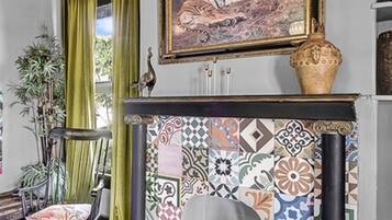 A room with a fireplace, a painting above it, and a patterned floor.