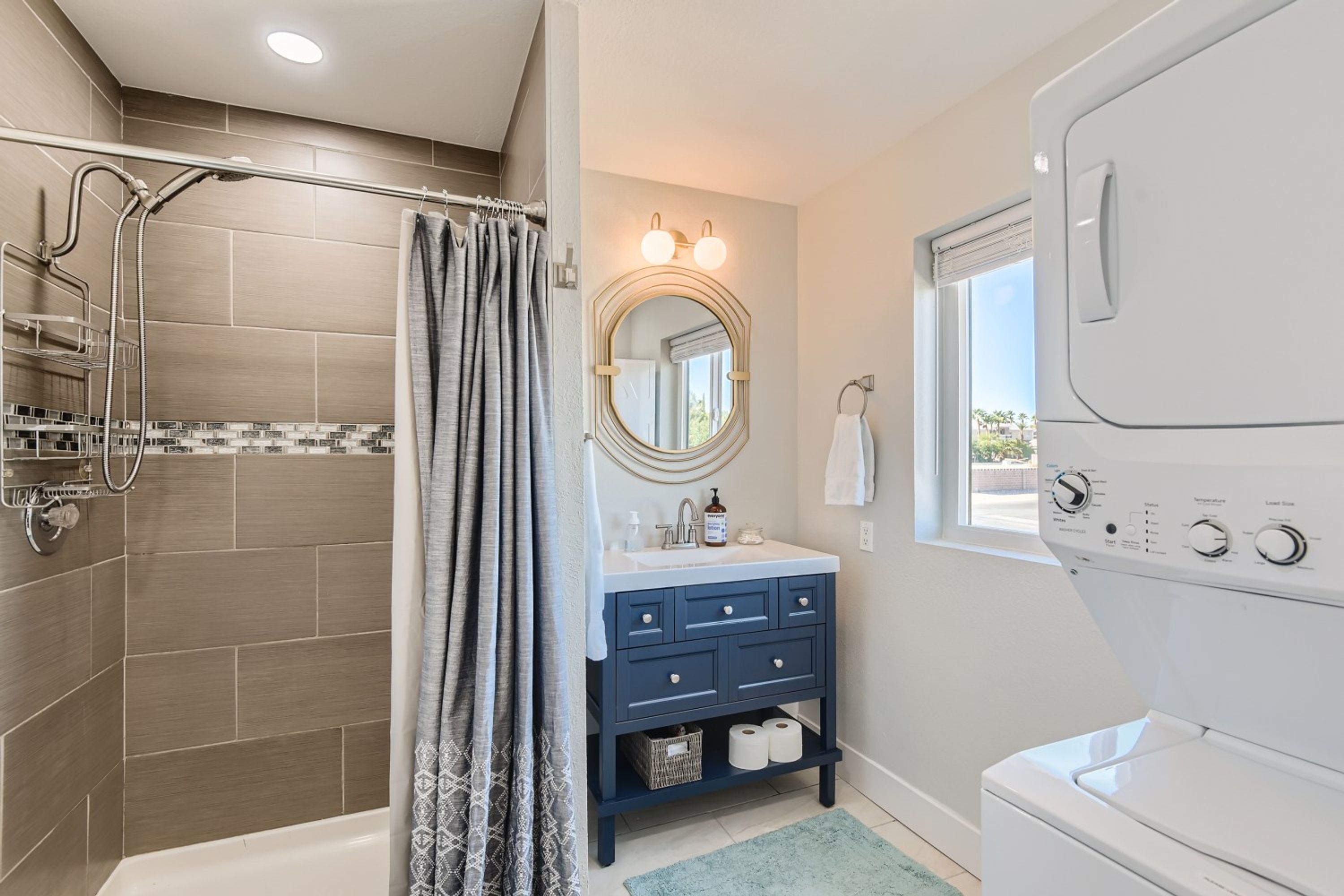 Une salle de bain moderne dotée d’une douche à l’italienne, d’un meuble-lavabo avec miroir et d’un lave-linge encastré.