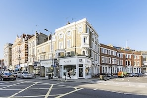 A street corner with a corner building housing a salon and a pharmacy.