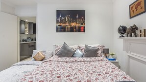A bedroom with a cityscape view, a bed with floral bedding, a globe, and a small table with a lamp. - Cute and Cosy Apartment in Kensington (London)