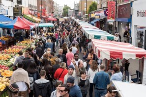 Un mercado al aire libre concurrido, con varios puestos y gente comprando.