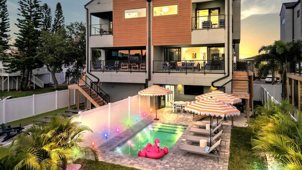 A modern two-story house with a swimming pool, outdoor seating, and a staircase leading to the upper floor. - NEW 4 Bed 3 Bath Heated Salt Pool Walk2beach (Indian Rocks Beach)