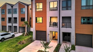 A modern multi-story residential building with a mix of wooden and concrete facades, large windows, and a visible car parked in the driveway. - NEW 4 Bed 3 Bath Heated Salt Pool Walk2beach (Indian Rocks Beach)