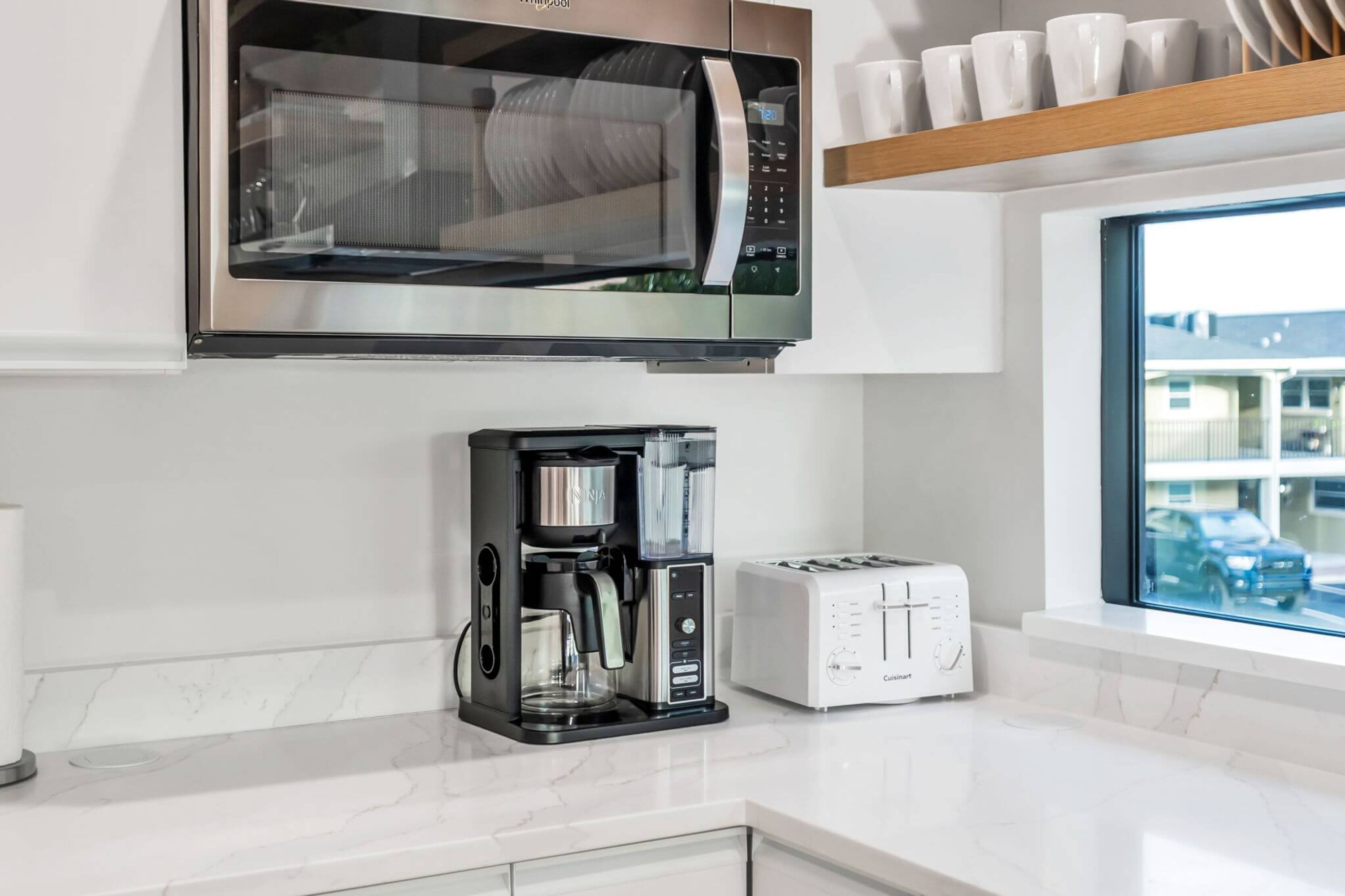 A modern kitchen with a built-in microwave, coffee maker, and toaster.