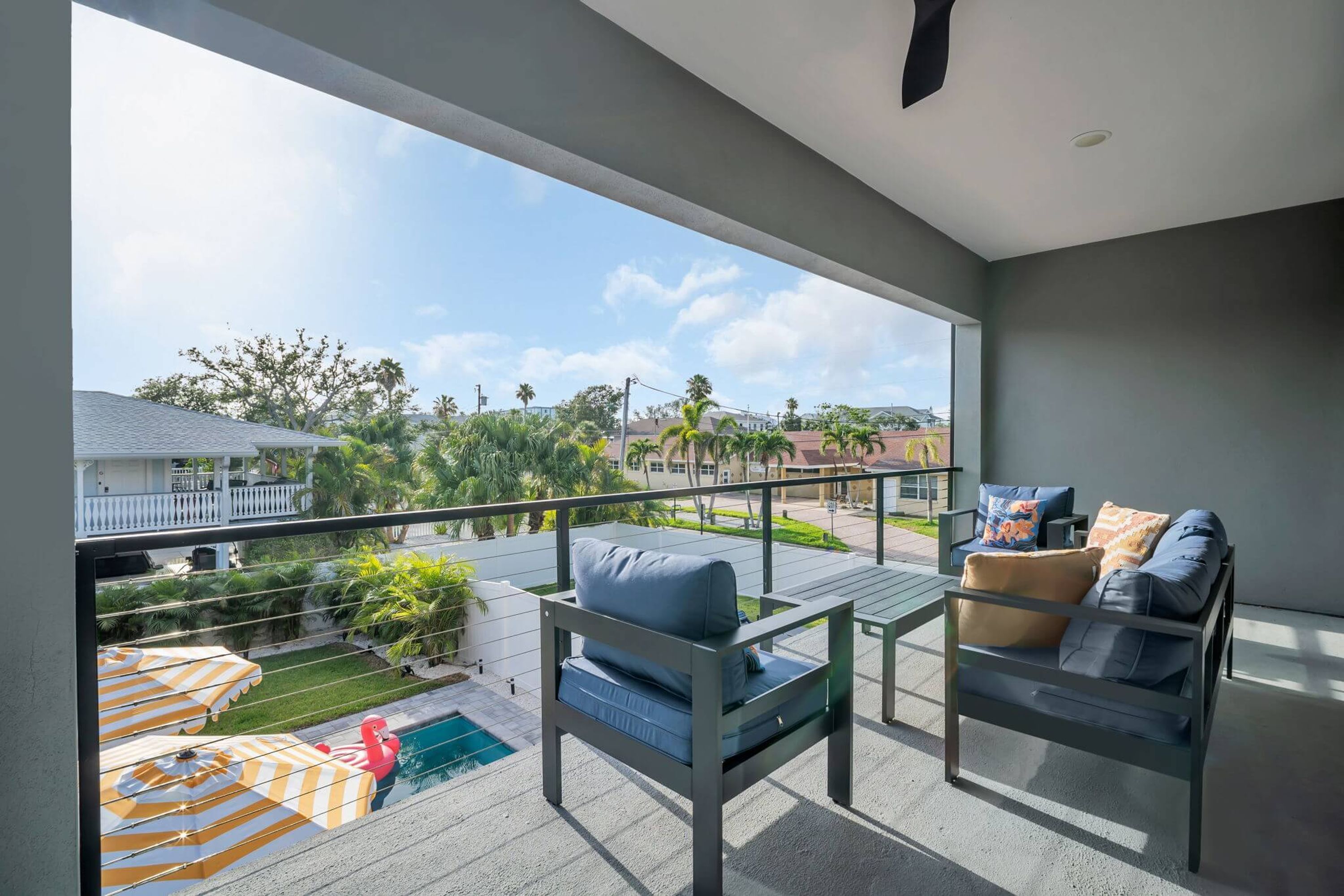 Ein Balkon mit Blick auf einen Pool, Gartenmöbel und einer Brüstung.